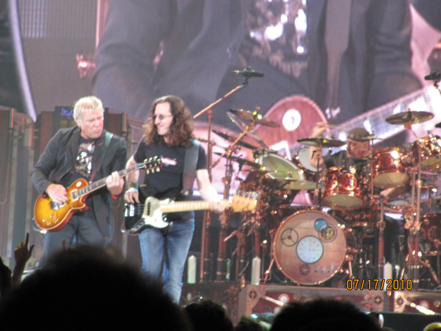 Rush performing on the Time Machine tour in 2010, with a clock face on the bass drum.