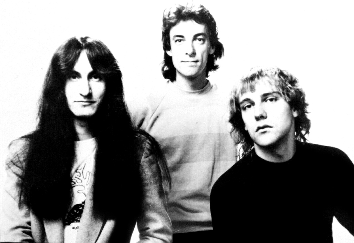 Black and white promotional portrait of Rush in the 1970s: Geddy Lee, Neil Peart and Alex Lifeson.